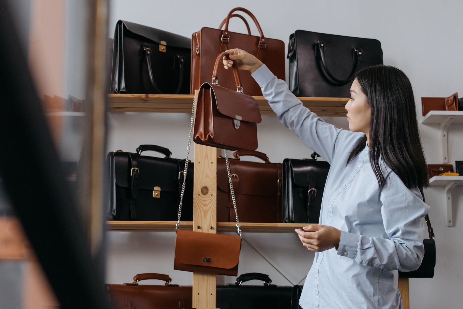 Femme qui choisit un sac en cuir sur un présentoir de maroquinerie